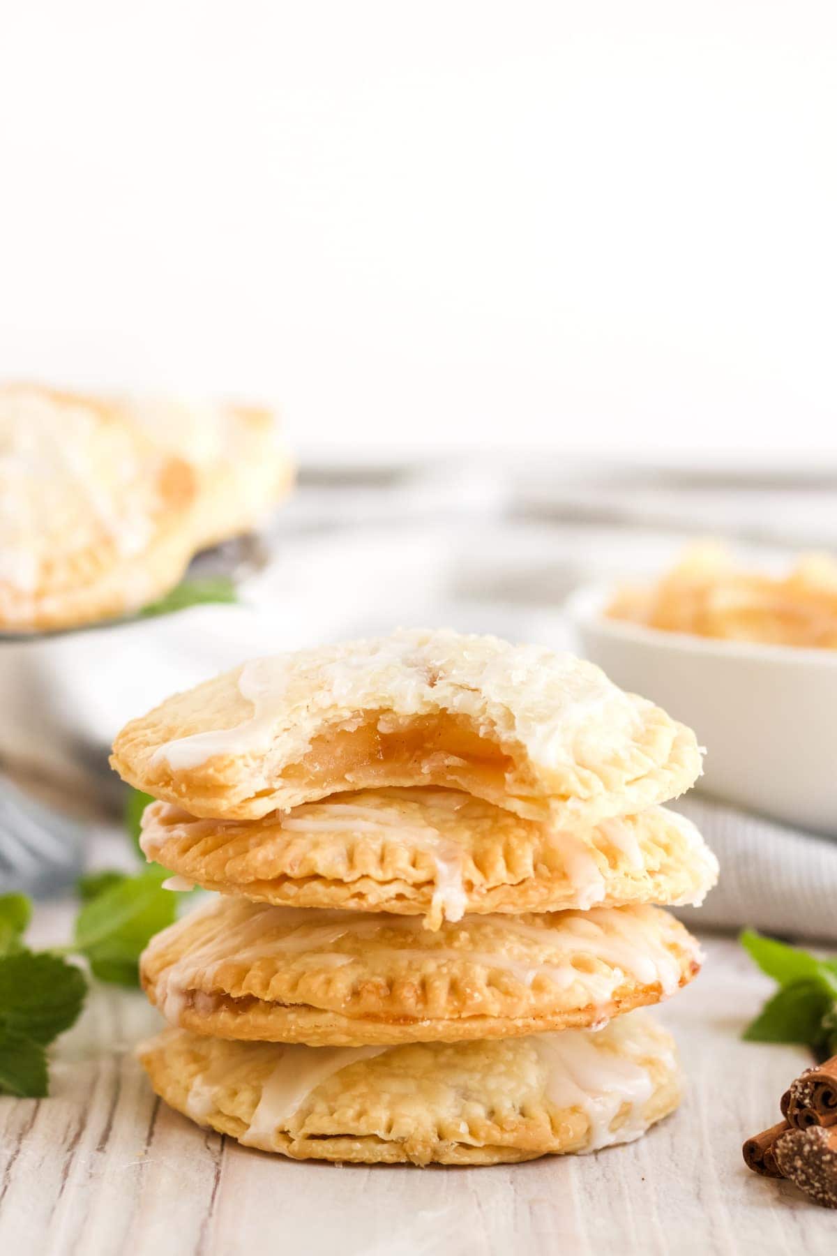 Air Fryer Apple Hand Pies stacked up with apple pie filling showing in the top pie. 