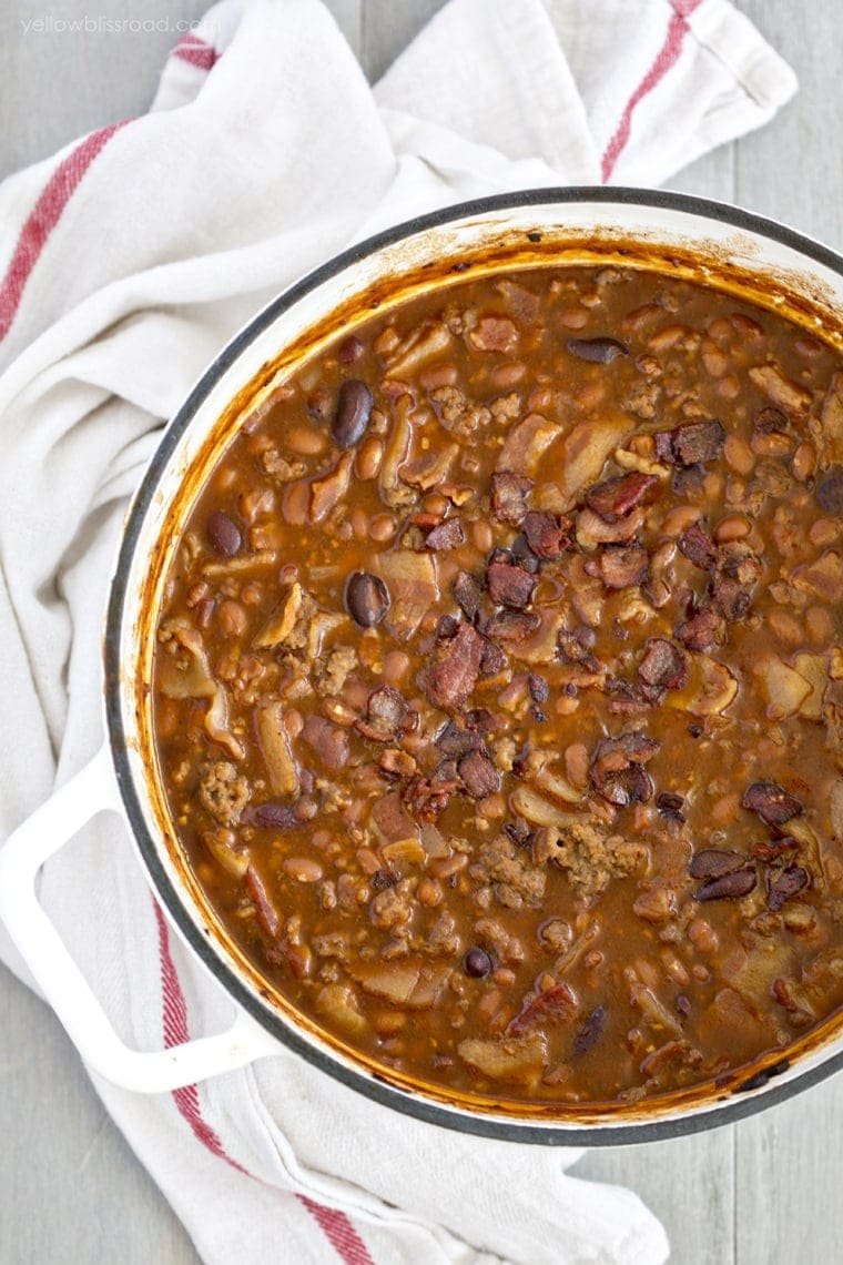 An overhead shot of a large white pot with baked beans, beef and bacon
