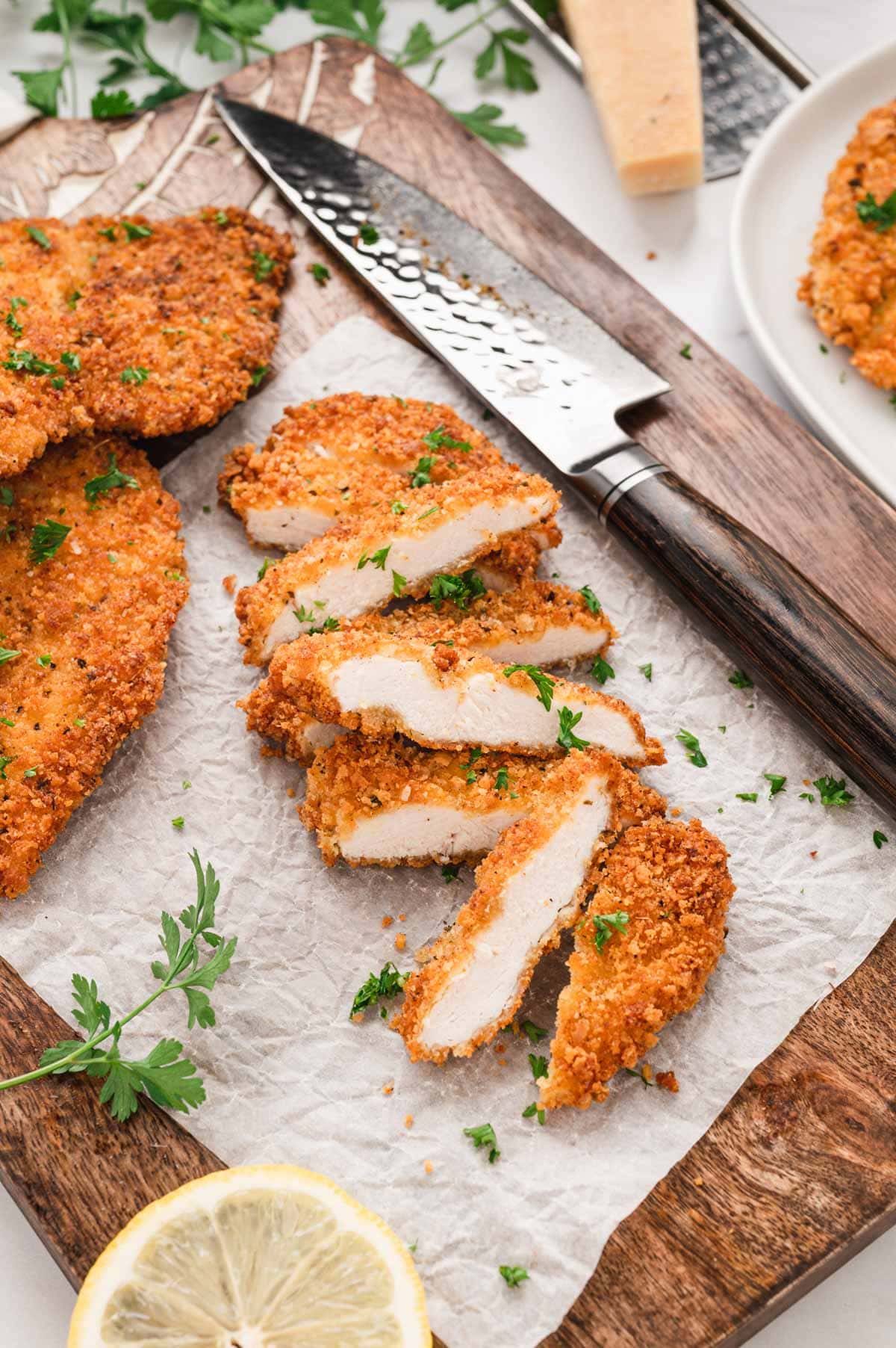 Sliced crispy chicken cutlet on a cutting board with a knife. 