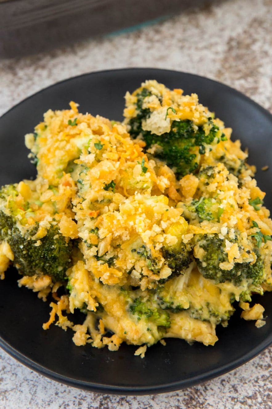 broccoli with cheese sauce and cracker topping on a black plate