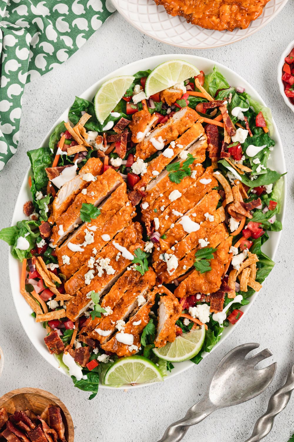 Crispy chicken with buffalo sauce on a bed of lettuce with tortilla strips and carrots.