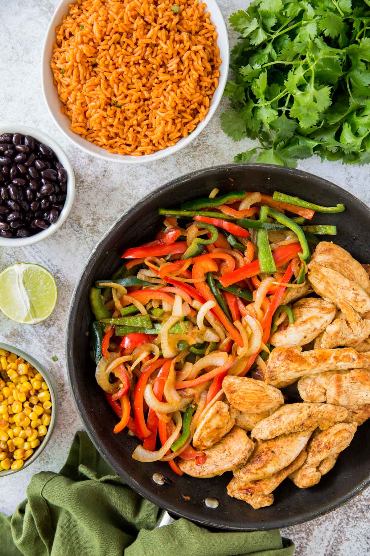 cast iron skillet, chicken, peppers, onions, rice, black beans, cilantro, limes, green napkin