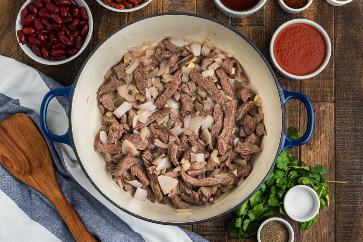 Browned meat and onions in a skillet.