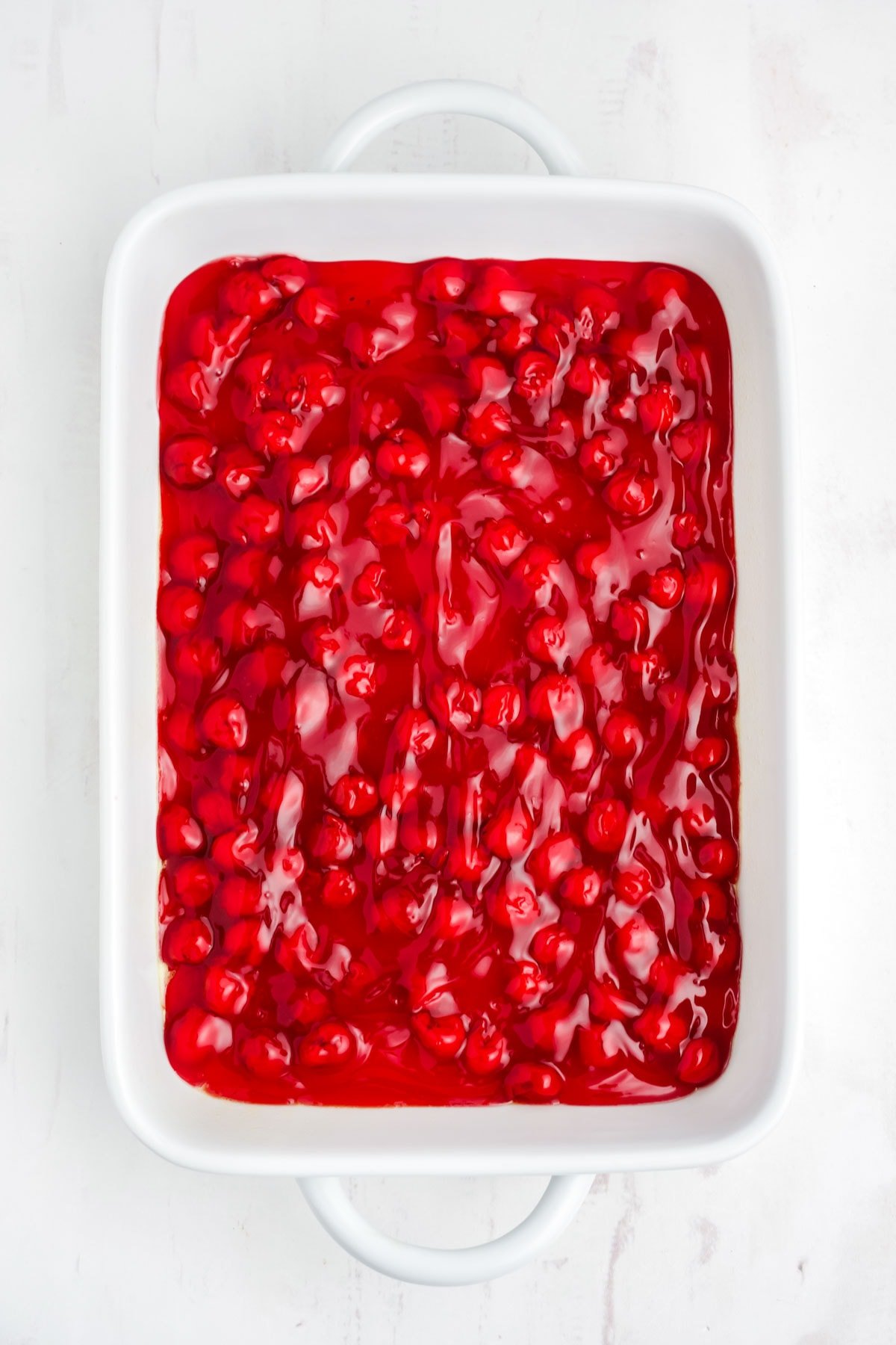 Cherry Pie filling spread into the bottom of a baking dish.