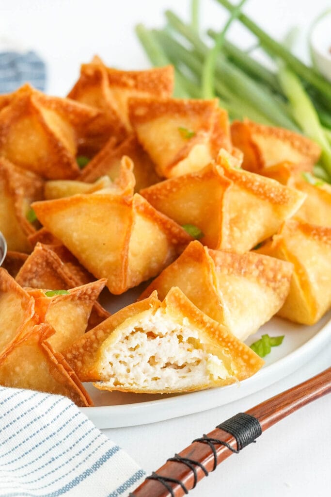 plate of wontons, one is cut in half to show the filling