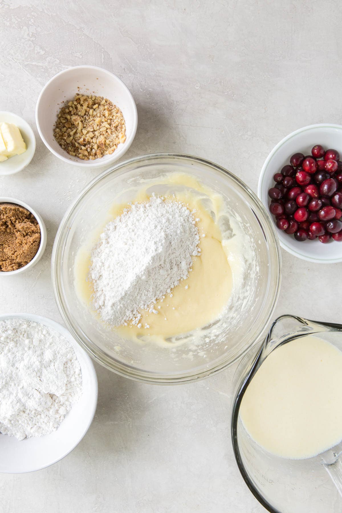 Flour added to a bowl of light yellow batter. 