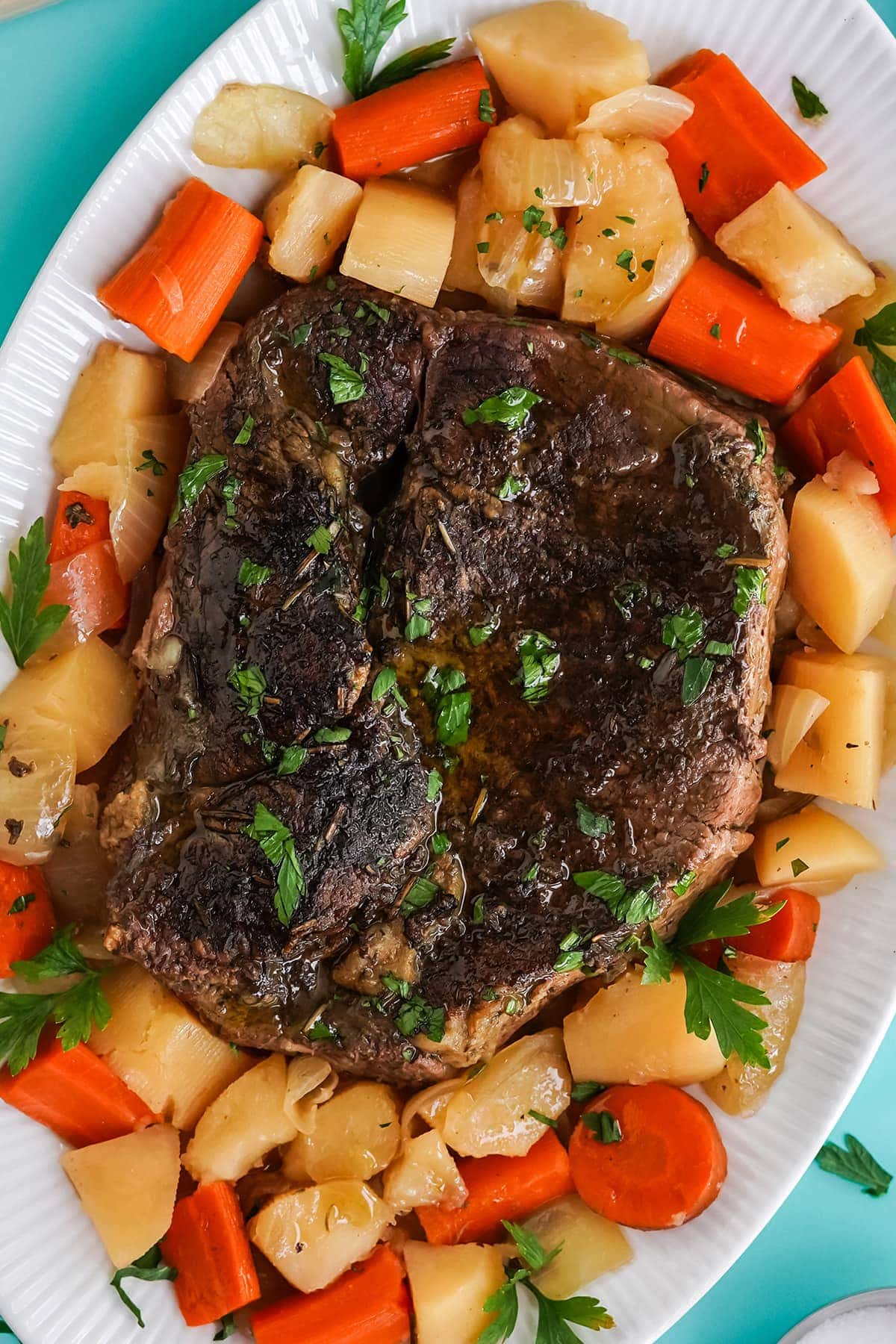 chuck roast, carrots, onions, potatoes on white serving platter