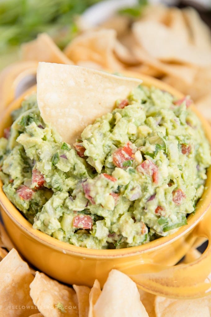 a chip in a bowl of the best guacamole