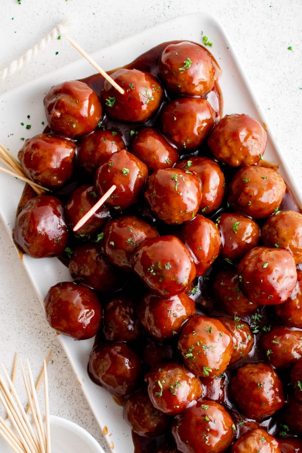 Grape Jelly Meatballs piled on a platter with a toothpick.