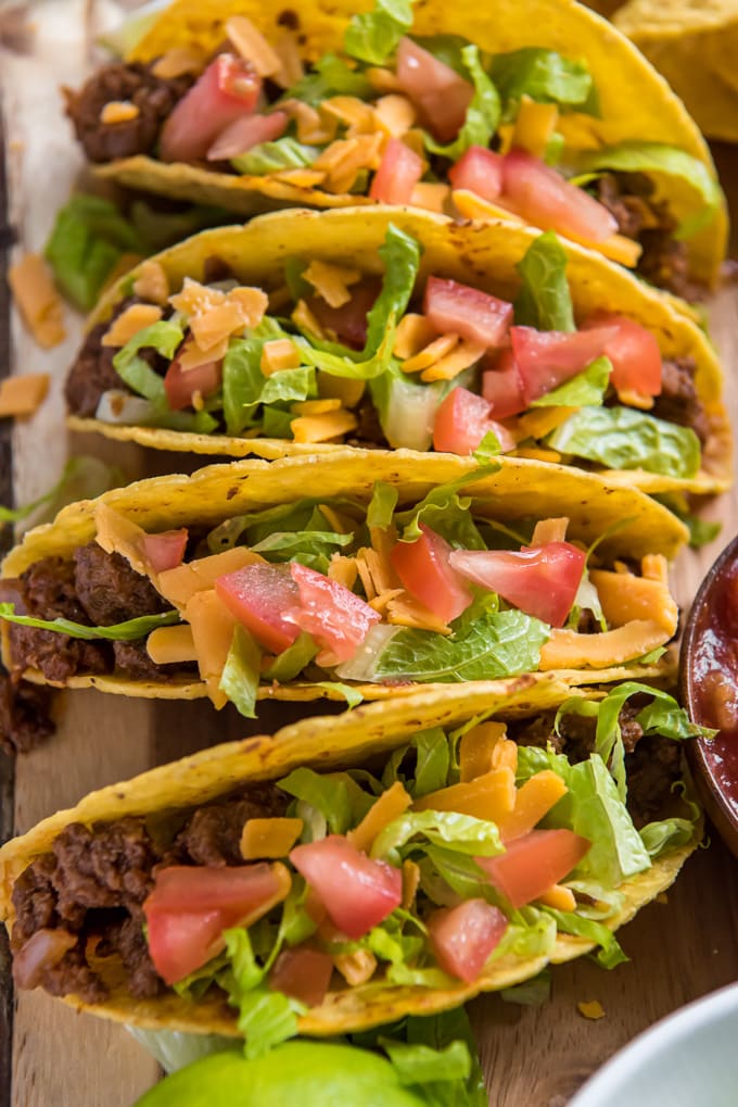 An overhead image of four tacos with ground beef, lettuce, cheese and tomatoes