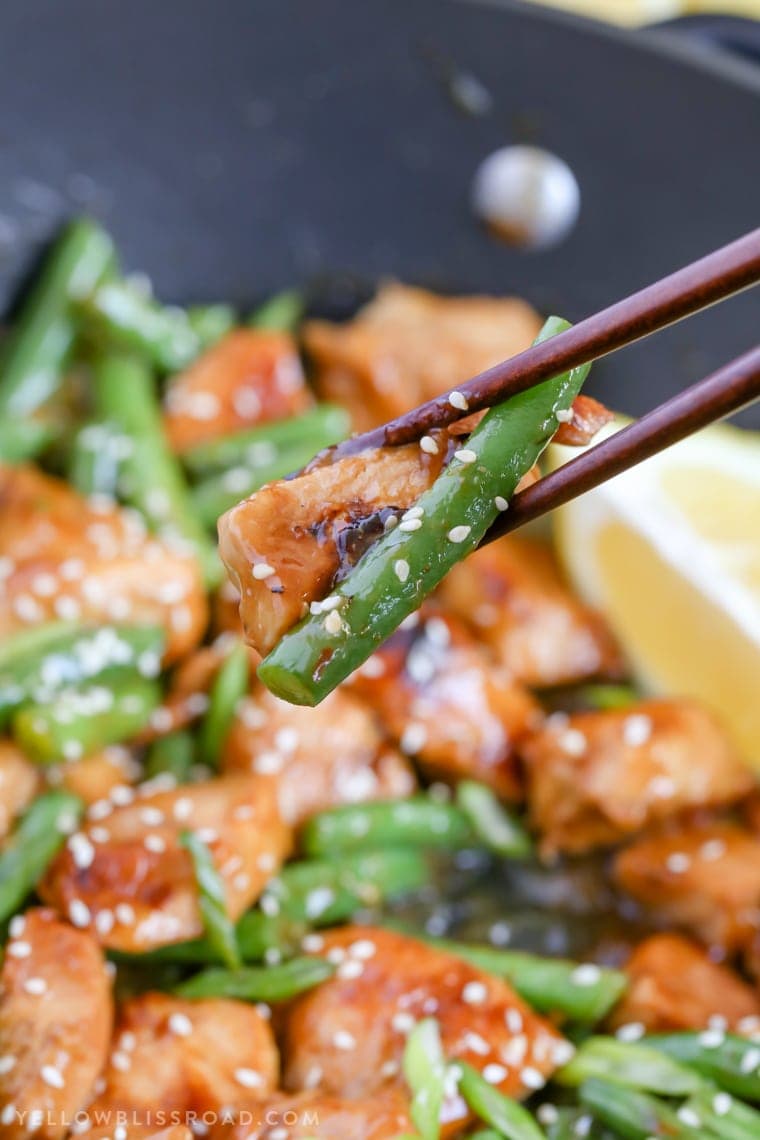 honey lemon chicken and green beans stir fry eaten with chopsticks.