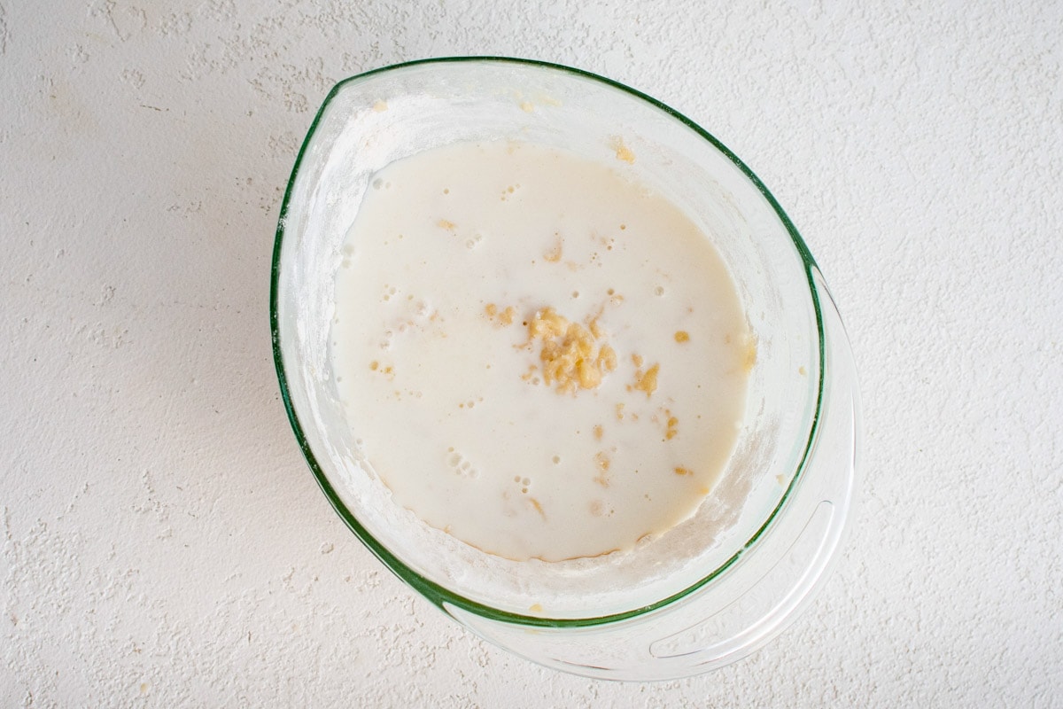 Adding milk to quick bread batter in a mixing bowl.