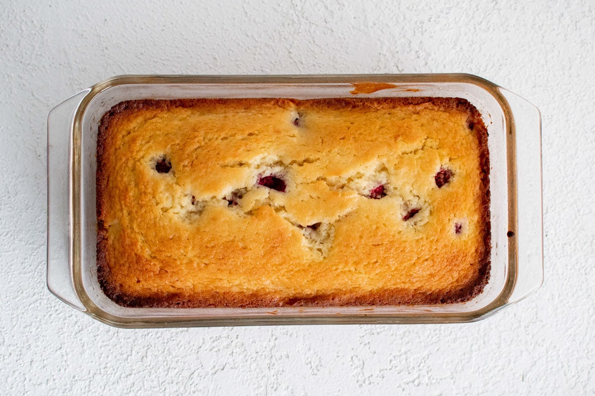 Baked loaf of lemon raspberry bread in a loaf pan.