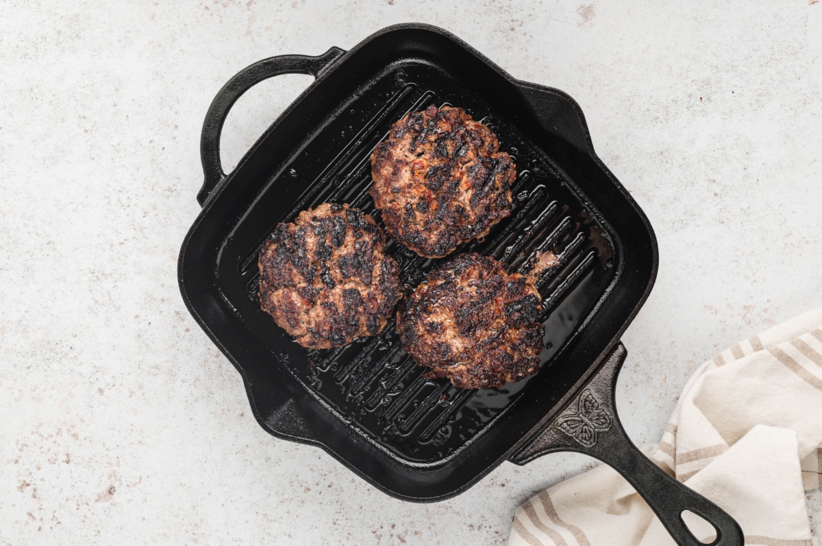 Burger patties cooking in a grill pan.