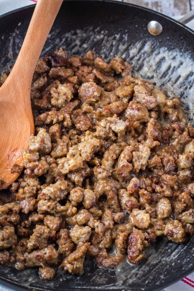 cooked sausage with butter and flour for gravy in a large skillet with a wooden spoon