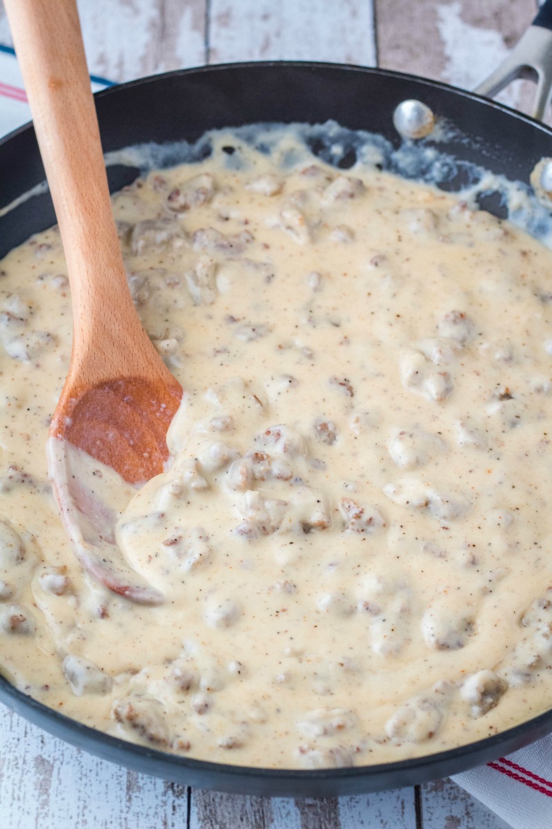 sausage gravy in a skillet after thickening, wooden spoon, black skillet