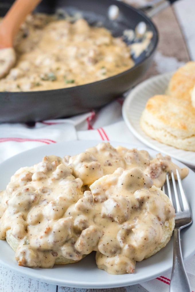 sausage gravy over biscuits, white plates, red and white napkin, for, skillet