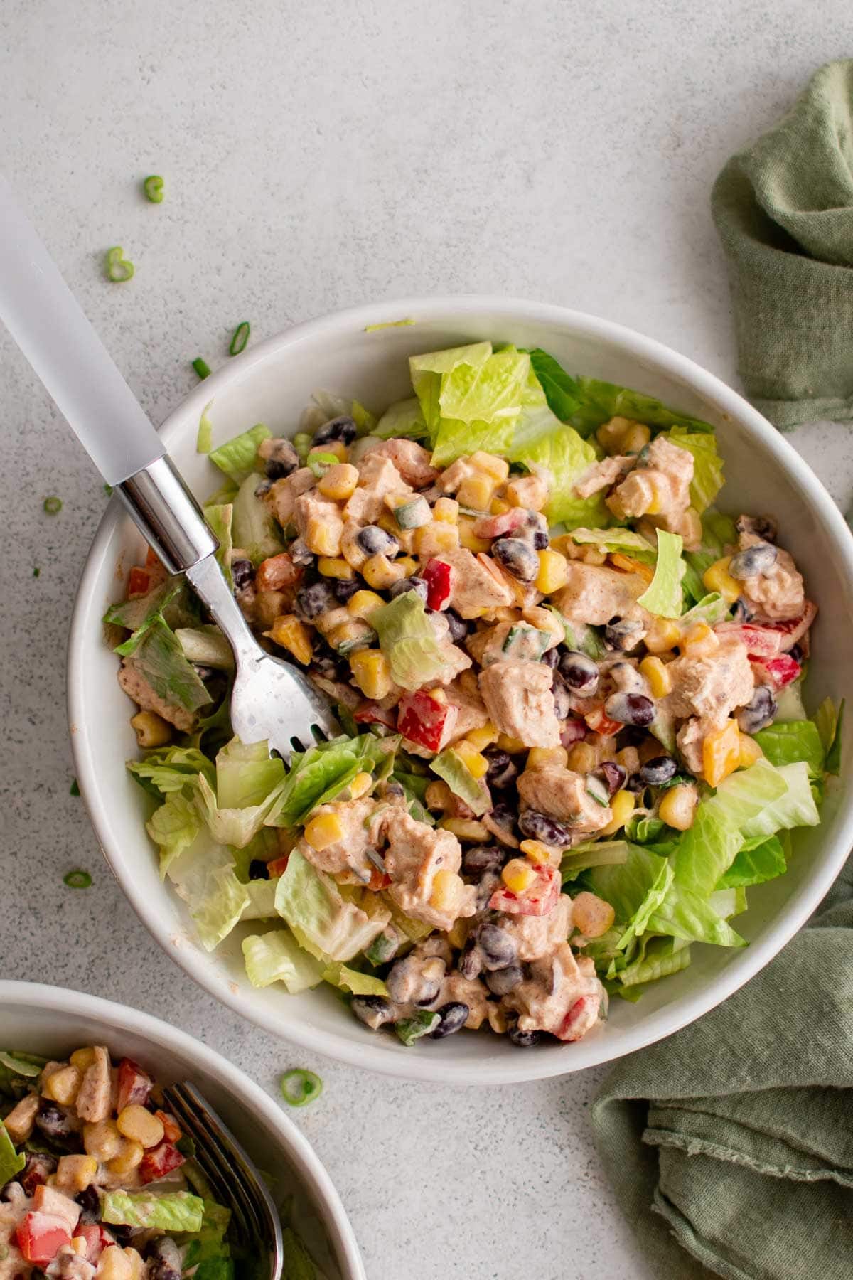 Southwest chicken salad on a bed of lettuce in a bowl with a fork.