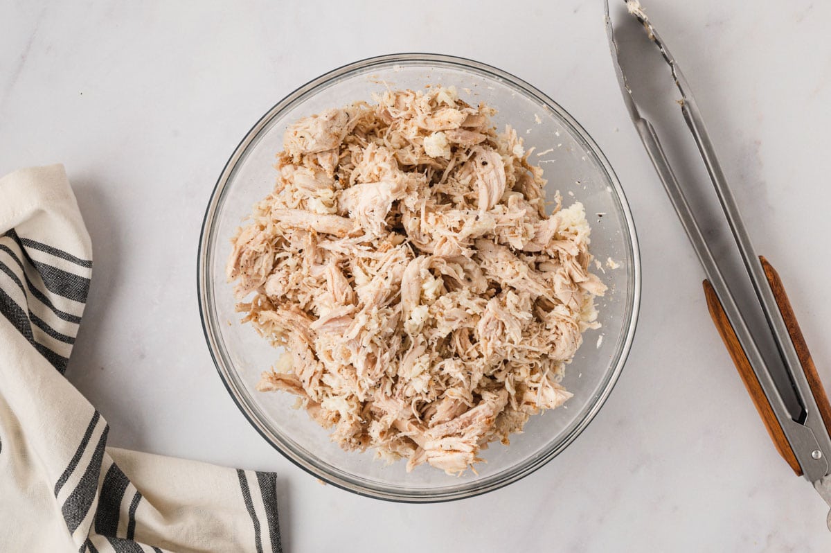 Shredded chicken in a clear glass bowl.